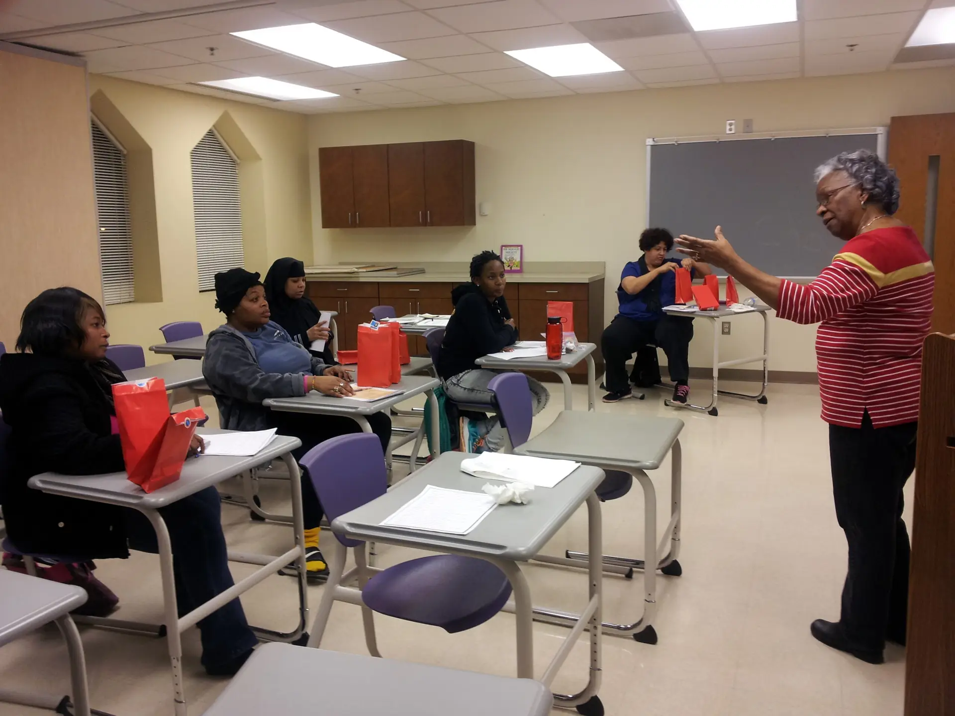 parenting class with 4 ladies sitting in desk learning from instructor